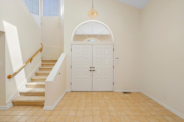 tiled entryway featuring an inviting chandelier and high vaulted ceiling