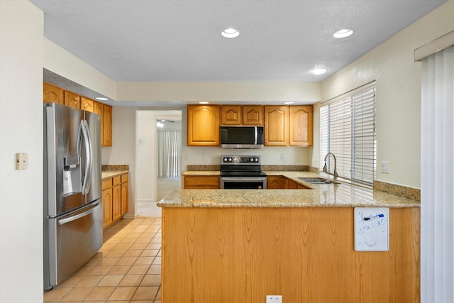 kitchen featuring a textured ceiling, sink, kitchen peninsula, stainless steel appliances, and light tile patterned floors