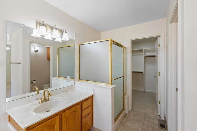 bathroom featuring a textured ceiling, walk in shower, tile patterned floors, vanity, and toilet