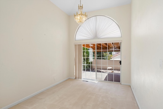 empty room featuring carpet flooring, a towering ceiling, and a chandelier