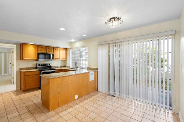 kitchen featuring light tile patterned floors, sink, appliances with stainless steel finishes, and kitchen peninsula