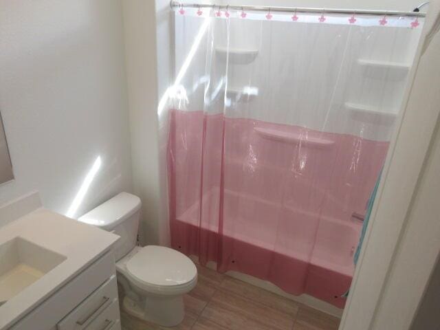 full bathroom with vanity, shower / bath combo, and toilet