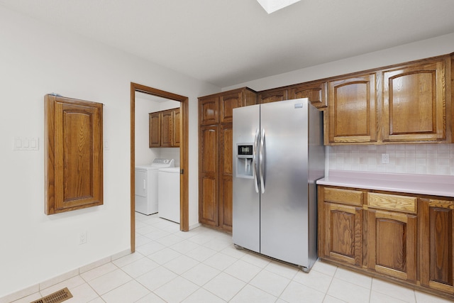 2616 Don Pedro NW, Albuquerque, NM 87104 - kitchen featuring light countertops, stainless steel fridge, decorative backsplash, washer and dryer, and brown cabinetry