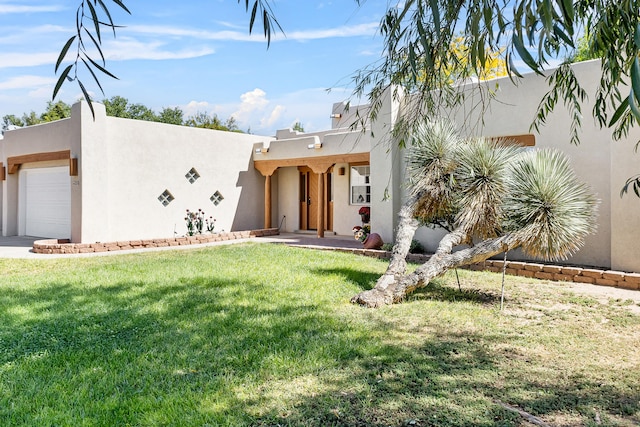 pueblo-style home with a garage and a front lawn