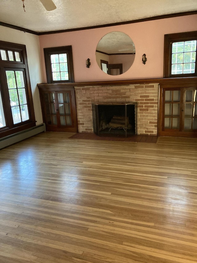 unfurnished living room featuring a fireplace, wood-type flooring, a textured ceiling, and a healthy amount of sunlight