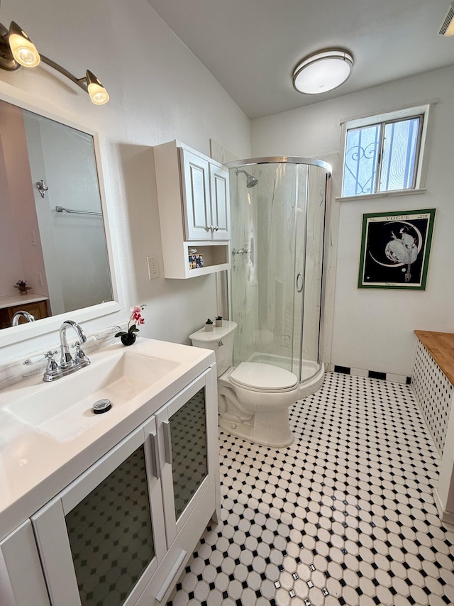 bathroom featuring toilet, vanity, an enclosed shower, and tile patterned flooring