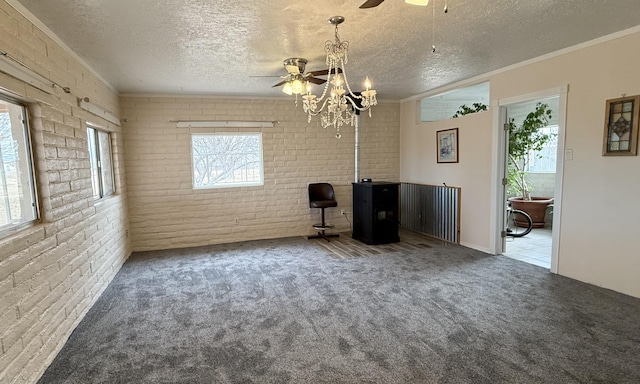 spare room featuring carpet floors, a healthy amount of sunlight, brick wall, and a textured ceiling