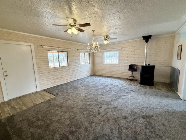 interior space featuring ceiling fan with notable chandelier, brick wall, a wealth of natural light, and a textured ceiling