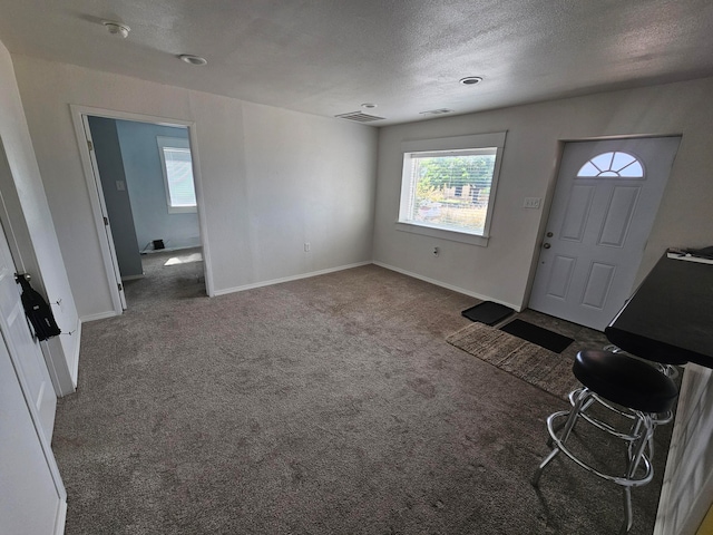 foyer with dark carpet and a textured ceiling