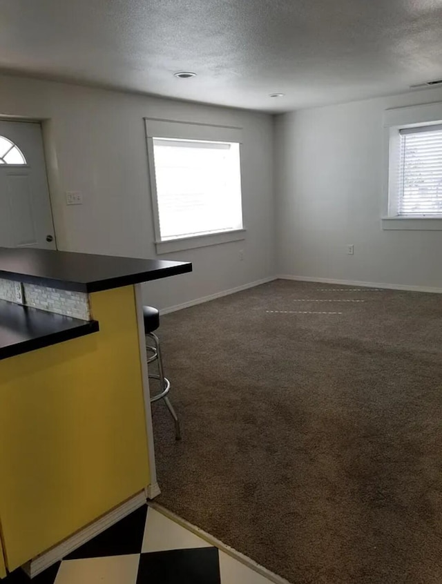 kitchen featuring dark carpet, a textured ceiling, and a kitchen bar