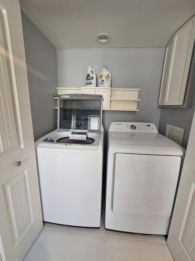 clothes washing area featuring light tile patterned floors and washing machine and dryer