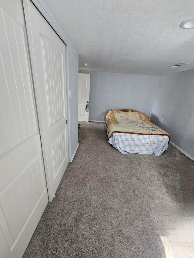 bedroom featuring dark carpet and a textured ceiling