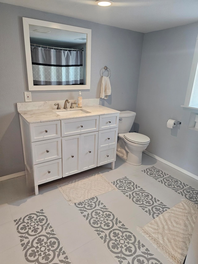 bathroom featuring tile patterned flooring, vanity, and toilet