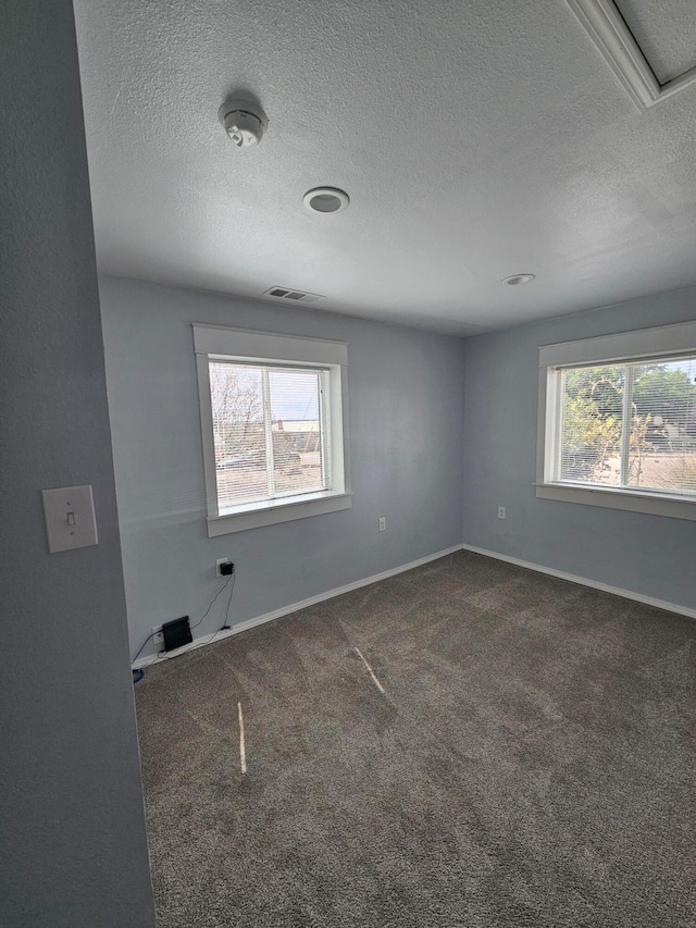 unfurnished room with a textured ceiling and dark carpet