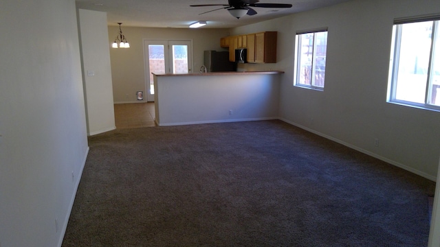 interior space with ceiling fan with notable chandelier, sink, and carpet