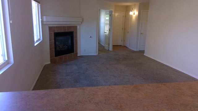 unfurnished living room featuring carpet and a tiled fireplace