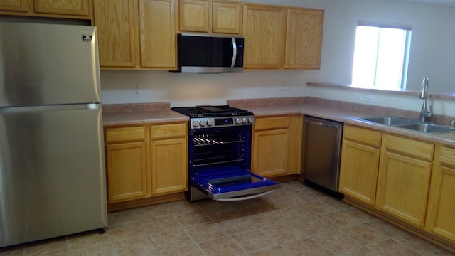 kitchen featuring stainless steel appliances, light brown cabinetry, and sink