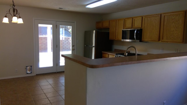 kitchen with sink, kitchen peninsula, an inviting chandelier, stainless steel appliances, and decorative light fixtures