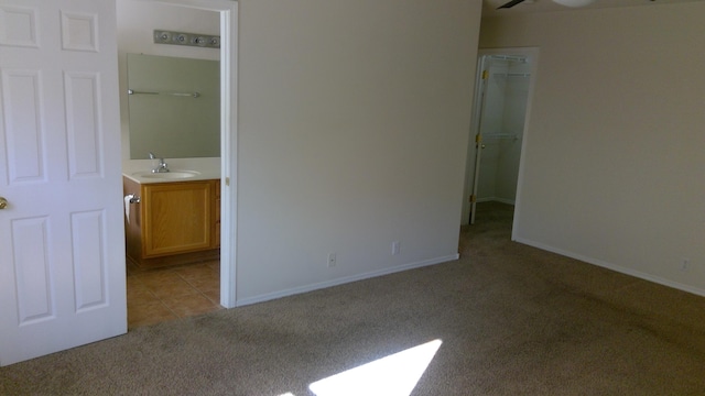 unfurnished bedroom featuring light carpet, ensuite bathroom, and sink