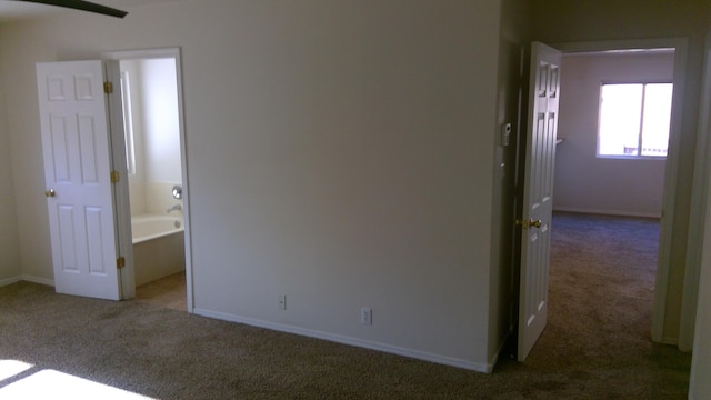 unfurnished bedroom featuring dark colored carpet and ensuite bath