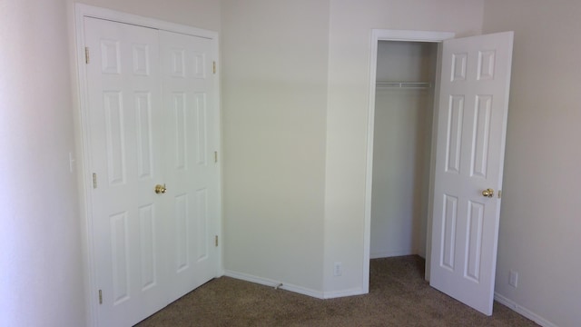 unfurnished bedroom with dark carpet and a closet