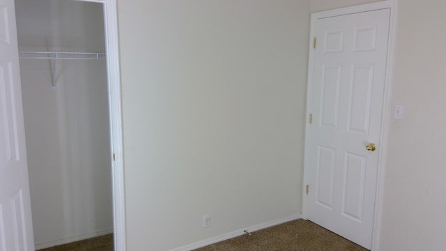 unfurnished bedroom with dark carpet and a closet