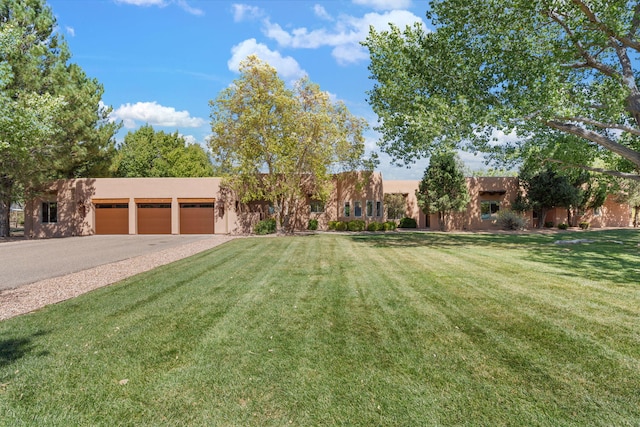 pueblo-style home featuring a front yard and a garage