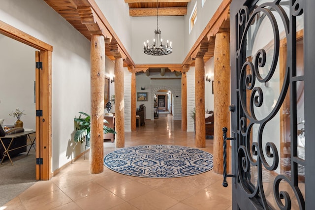 interior space featuring light tile patterned floors, an inviting chandelier, beam ceiling, and decorative columns