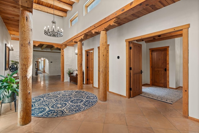 hall featuring wood ceiling, light tile patterned floors, beam ceiling, a notable chandelier, and ornate columns