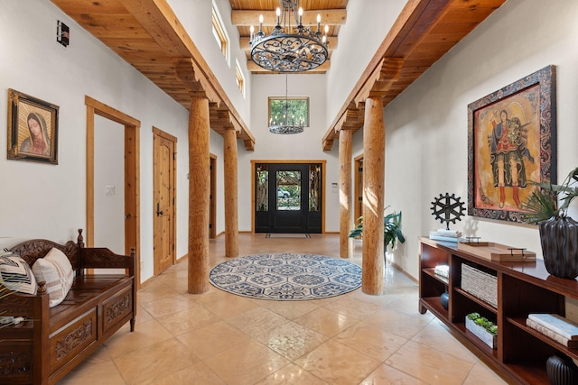 entrance foyer featuring a high ceiling, a chandelier, wooden ceiling, and ornate columns