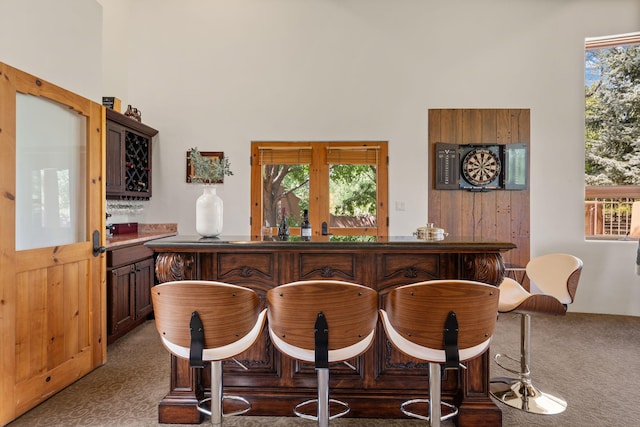 bar with french doors, a high ceiling, plenty of natural light, and carpet floors