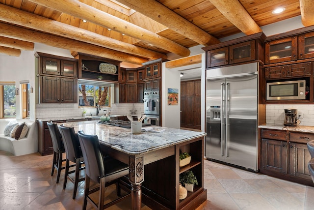 kitchen featuring a center island, built in appliances, light stone counters, and plenty of natural light