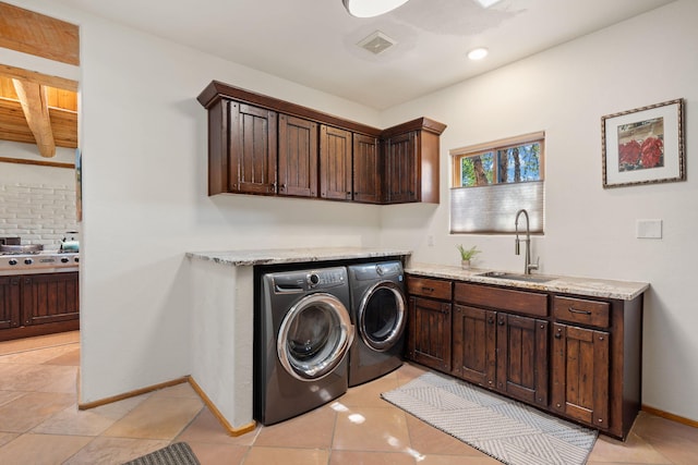 laundry room featuring washing machine and dryer, sink, light tile patterned floors, and cabinets