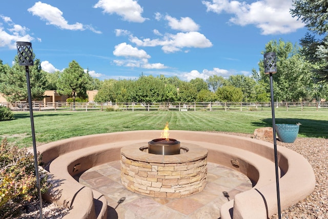 view of property's community featuring a rural view, a lawn, a patio, and an outdoor fire pit