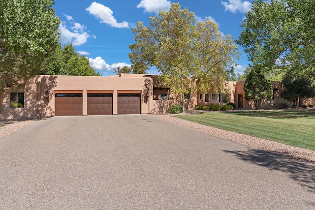 pueblo-style home featuring a front lawn and a garage