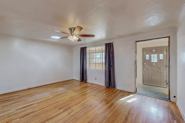 unfurnished room featuring a textured ceiling, light wood-type flooring, and ceiling fan