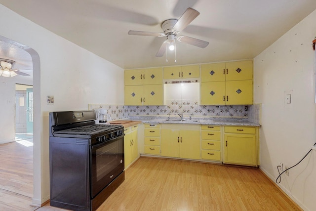 kitchen with light wood-type flooring, sink, black range with gas cooktop, and tasteful backsplash