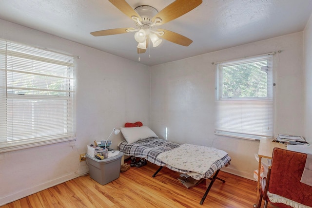 bedroom featuring ceiling fan, light wood-type flooring, and multiple windows