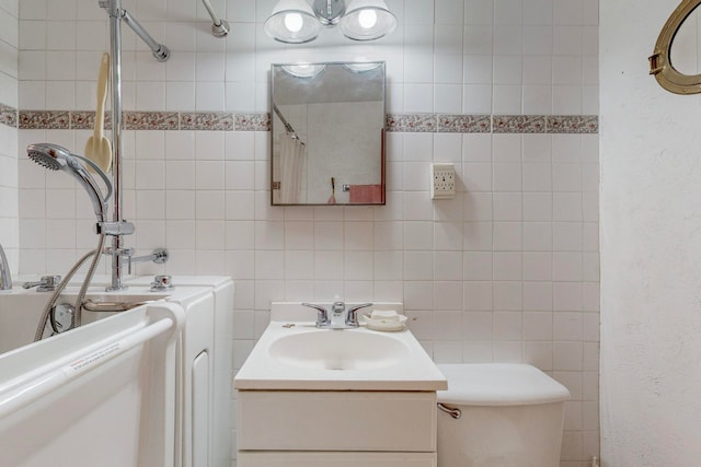 bathroom with tile walls, curtained shower, vanity, and toilet