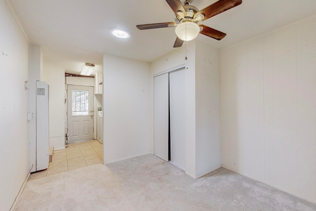 unfurnished bedroom featuring ceiling fan, light colored carpet, and a closet