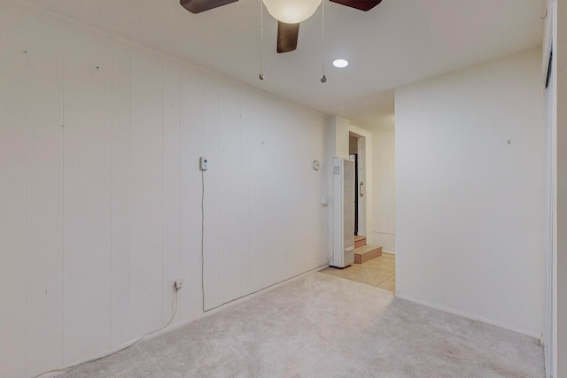 carpeted empty room featuring ceiling fan and wooden walls