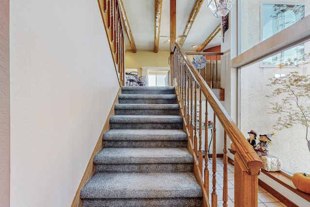 staircase with a towering ceiling, tile patterned floors, and beamed ceiling