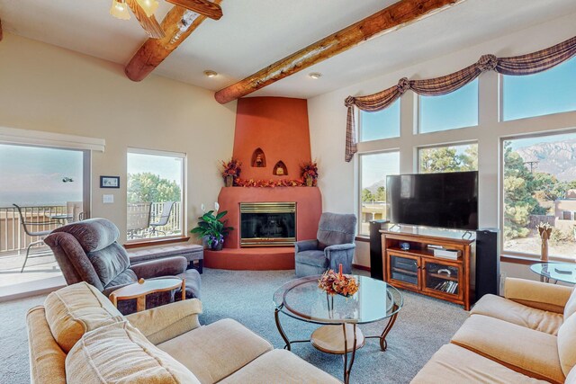 living room featuring beam ceiling, carpet, plenty of natural light, and a fireplace