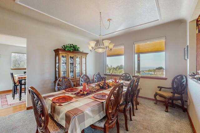 dining space with a chandelier, light carpet, and a textured ceiling