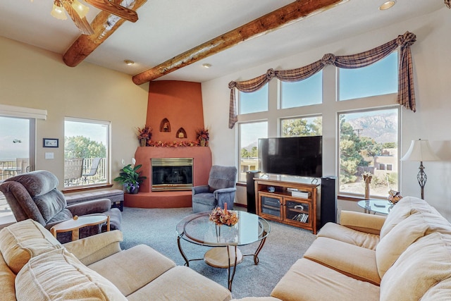 carpeted living room featuring beamed ceiling, ceiling fan, a healthy amount of sunlight, and a fireplace