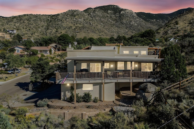 back house at dusk featuring a balcony and a mountain view