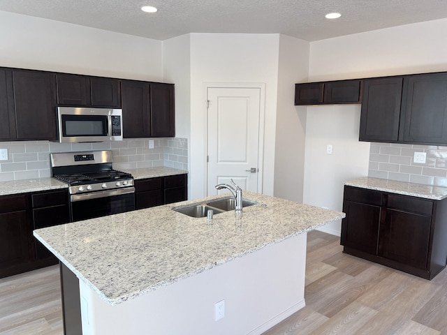 kitchen with a center island with sink, stainless steel appliances, sink, and light hardwood / wood-style flooring