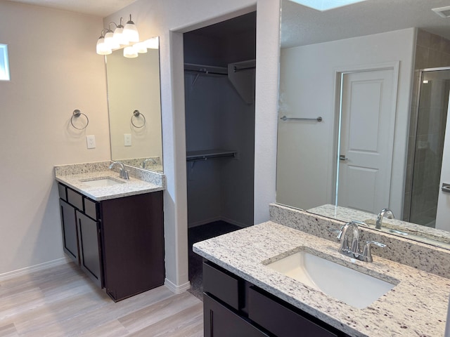 bathroom with hardwood / wood-style floors, a textured ceiling, walk in shower, and vanity