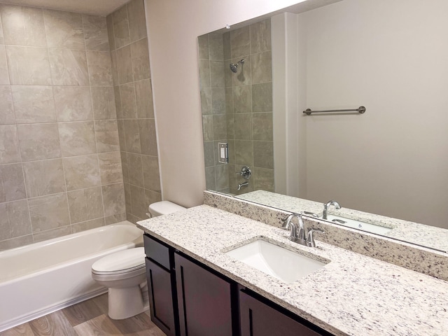 full bathroom with vanity, tiled shower / bath combo, hardwood / wood-style floors, and toilet