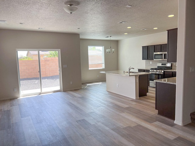 kitchen featuring a center island with sink, light hardwood / wood-style flooring, stainless steel appliances, and a chandelier